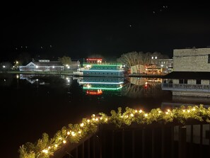 A waterfront hotel with a reflection in the water, a boat docked nearby, and a building with a clock tower.