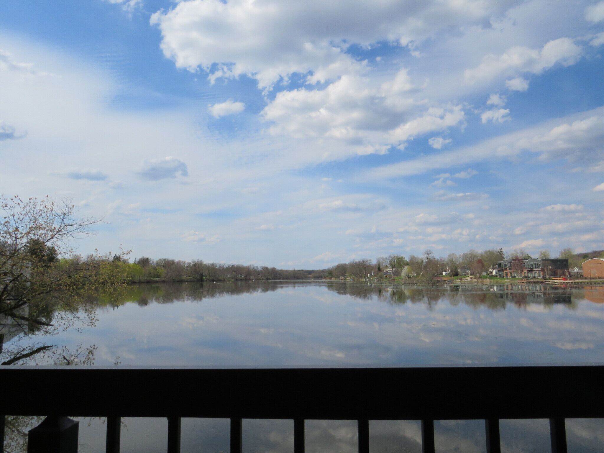 A calm lake with a clear sky and a distant shoreline with buildings.