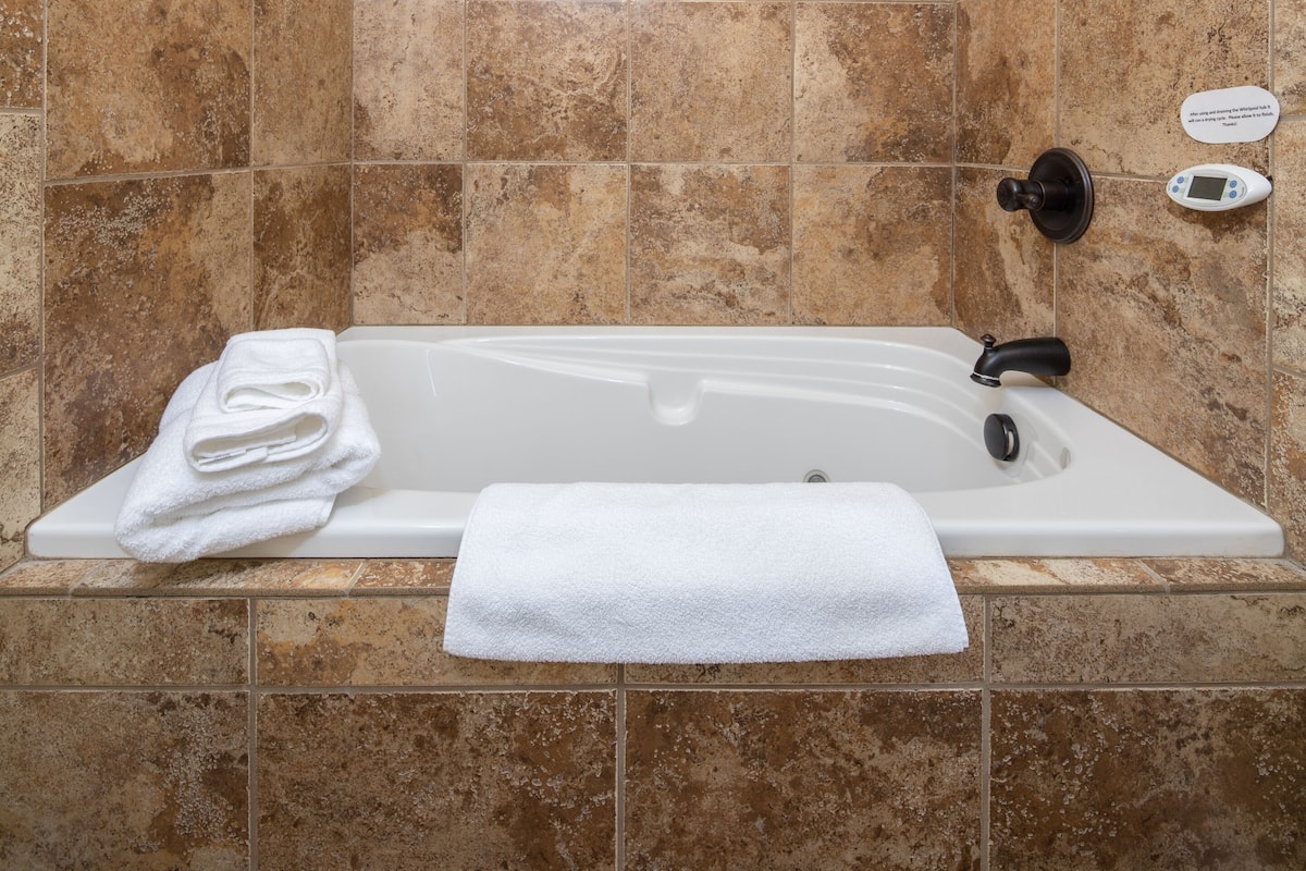 A modern bathroom with a bathtub, a towel, and a digital control panel.