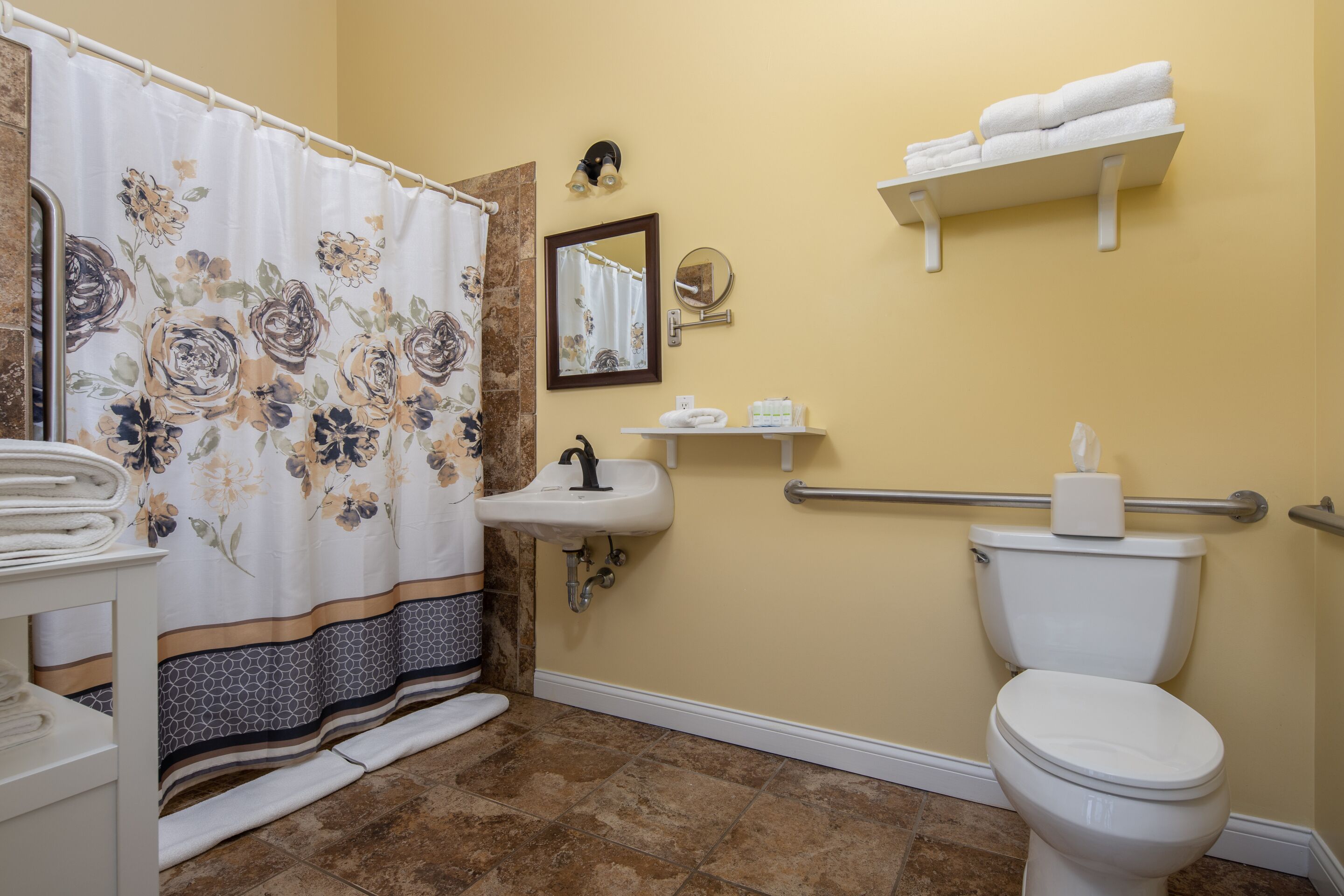 A bathroom with a shower curtain, sink, mirror, toilet, and towel rack.