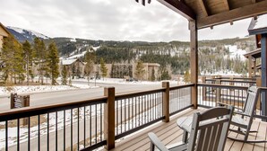 A wooden deck with a view of a snow-covered mountain and a road. - River Run Townhome RR42 (Keystone)