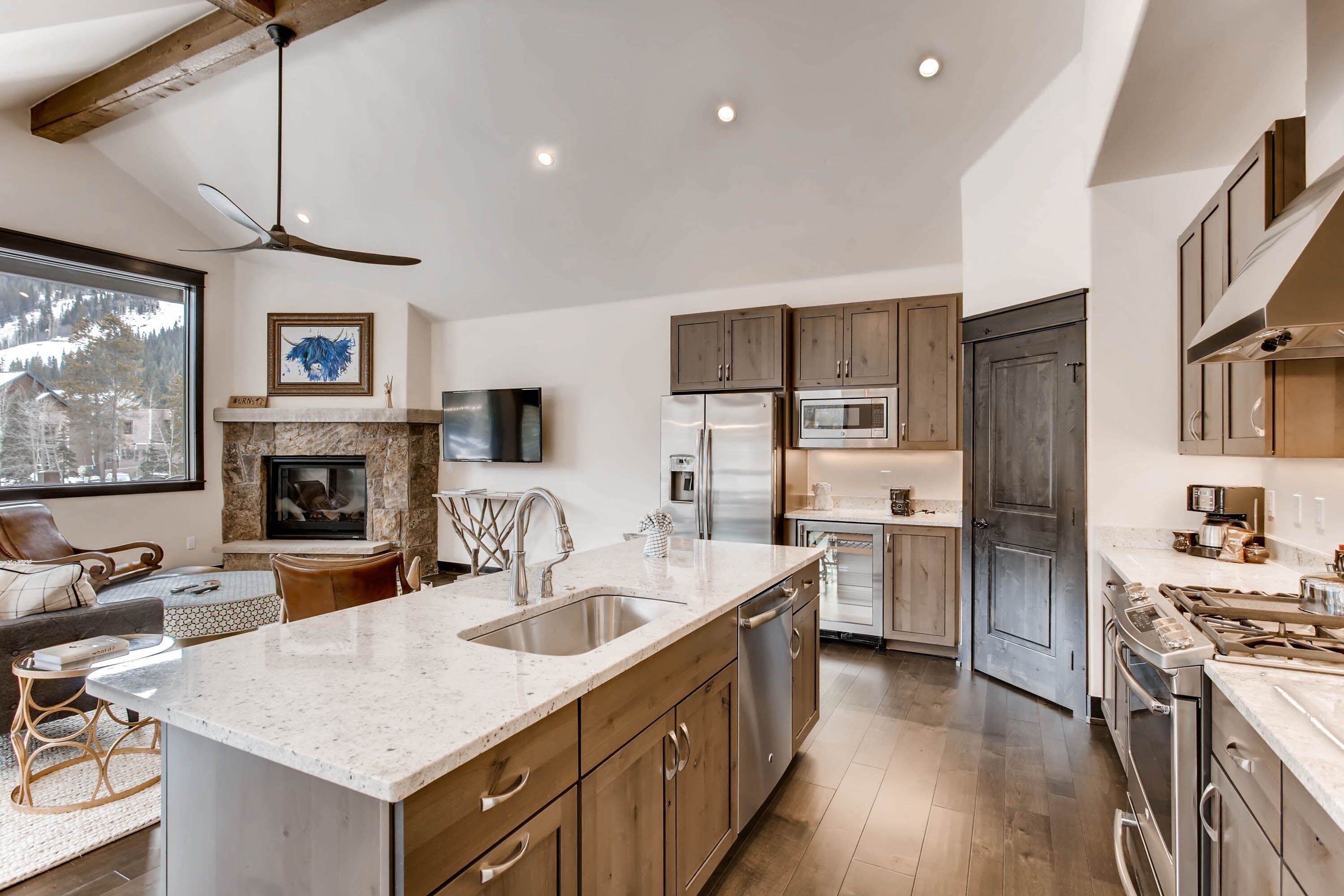 A modern kitchen with a large island, stainless steel appliances, and wooden cabinets.