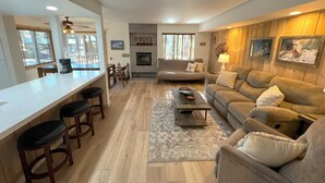 A modern living room with a sofa, coffee table, and bar area with stools. - Standard Condos with Free Parking (Mammoth Lakes)