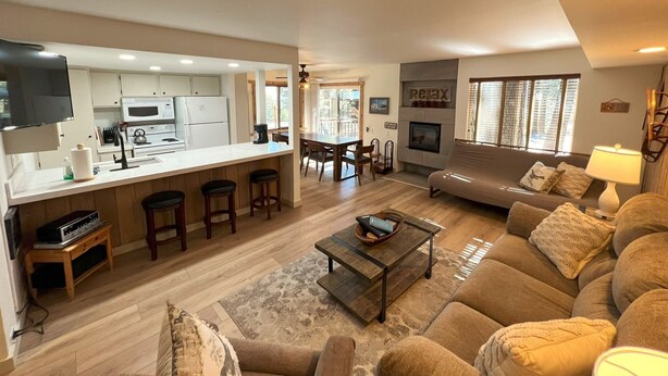 A spacious living area with a sofa, coffee table, and a kitchen area with a bar. - Standard Condos with Free Parking (Mammoth Lakes)