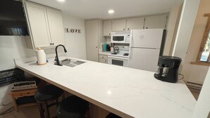 A modern kitchen with a white countertop, a sink, a coffee maker, and a microwave. - Standard Condos with Free Parking (Mammoth Lakes)