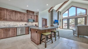 A spacious kitchen with wooden cabinets, a marble countertop, and a large island with stools.