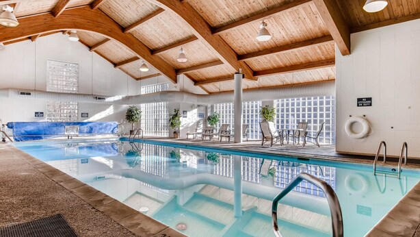 An indoor swimming pool with wooden beams, clear glass walls, and a blue pool cover. - Quicksilver 1662 (Keystone)