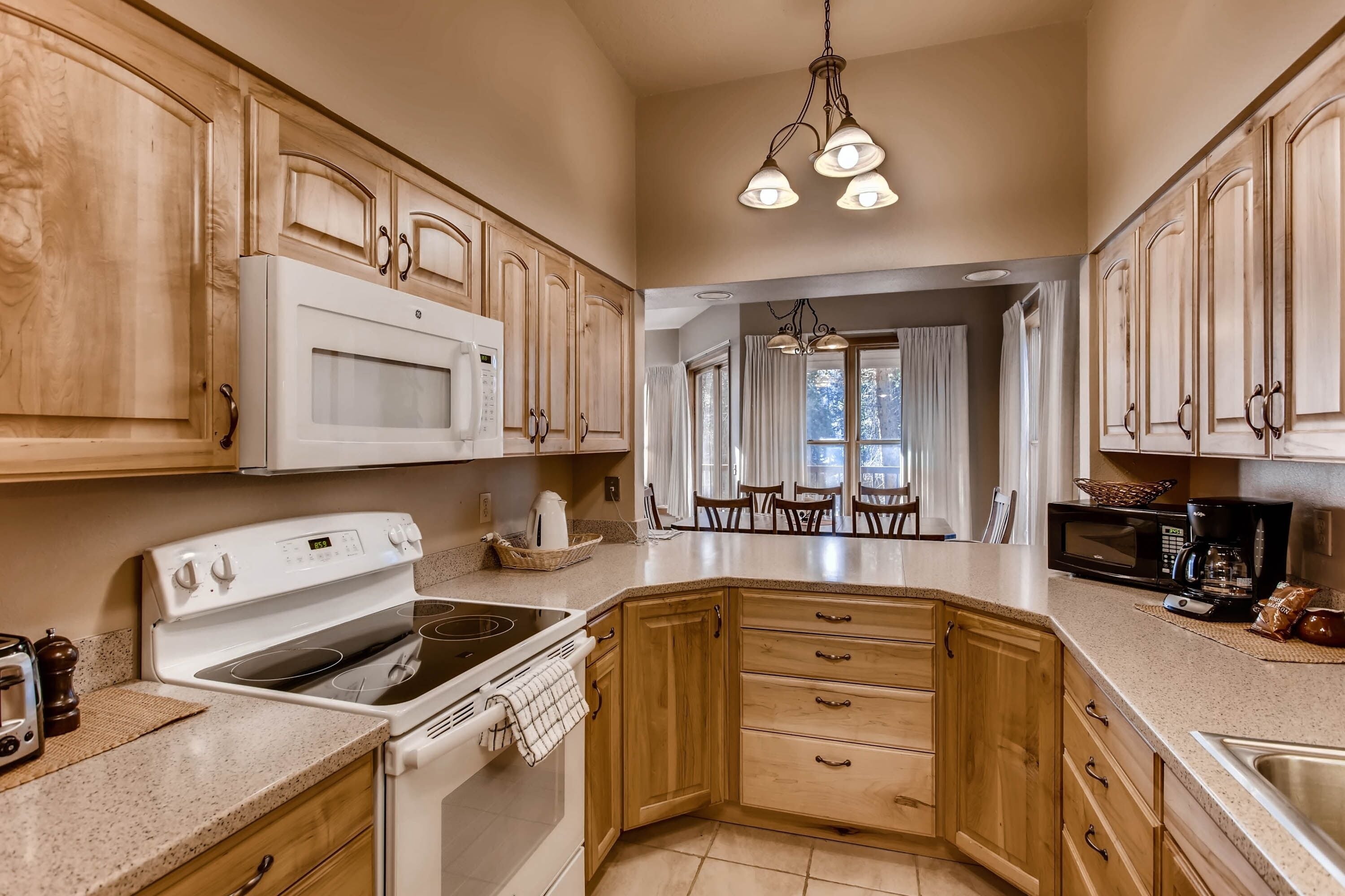 A kitchen with wooden cabinets, a white stove, and a dining area with a table and chairs.