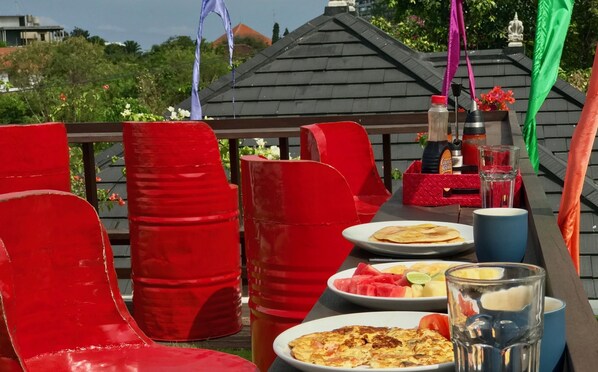 A dining area with red chairs and a table set with plates of food, glasses, and condiments.