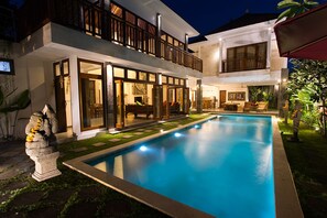 A two-story house with a swimming pool, large windows, and a balcony.