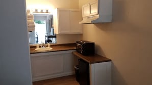 A compact kitchen with a sink, countertop, and a microwave.
