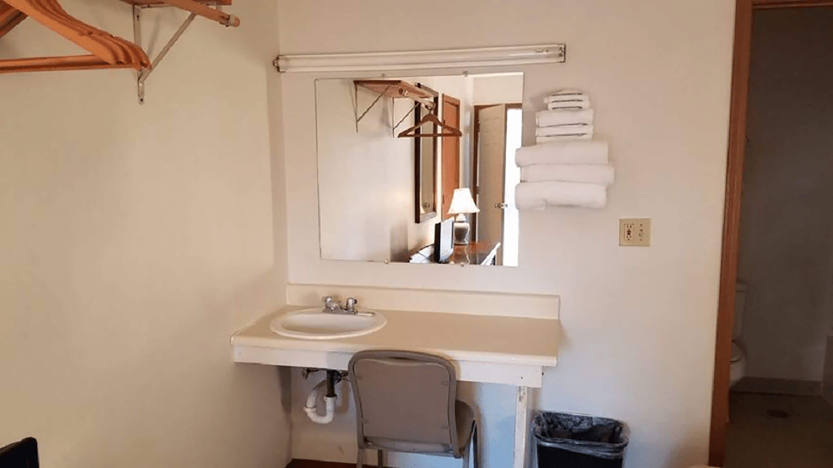 A bathroom with a white sink, mirror, and towel rack.