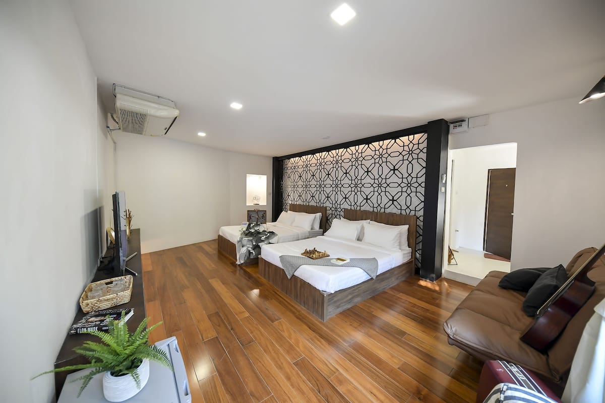 Une chambre d’hôtel moderne avec un grand lit, un canapé, une télévision et un panneau décoratif mural.