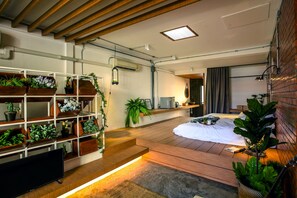 Une chambre moderne avec un plancher en bois, un lit, une télévision et une étagère ornée de plantes.