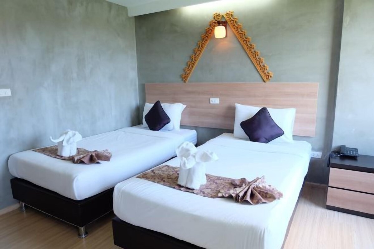 A hotel room with two beds, a wooden headboard, a nightstand, and a decorative wall piece.