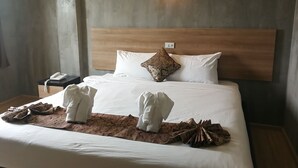 Una habitación de hotel con una cama grande, cabecera de madera, teléfono en la mesita de noche y lámpara de pared.