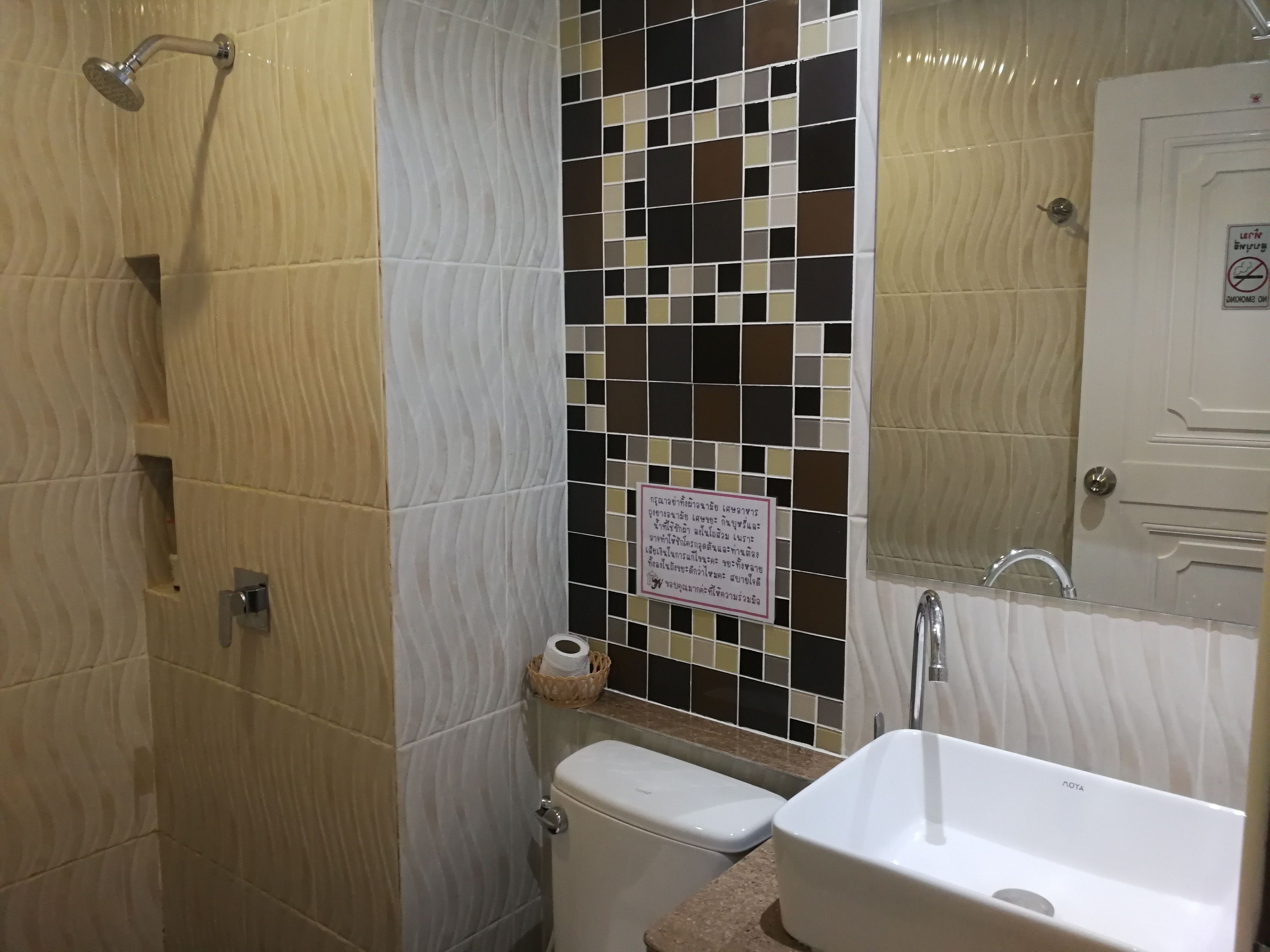 A bathroom with a shower, toilet, sink, and a mosaic tile wall.