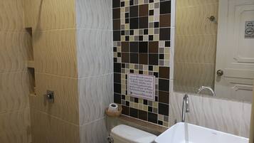 A bathroom with a shower, toilet, sink, and a mosaic tile wall.