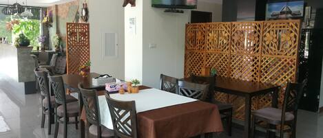 Un comedor con una mesa y sillas de madera, un televisor montado en la pared y un panel decorativo de madera.