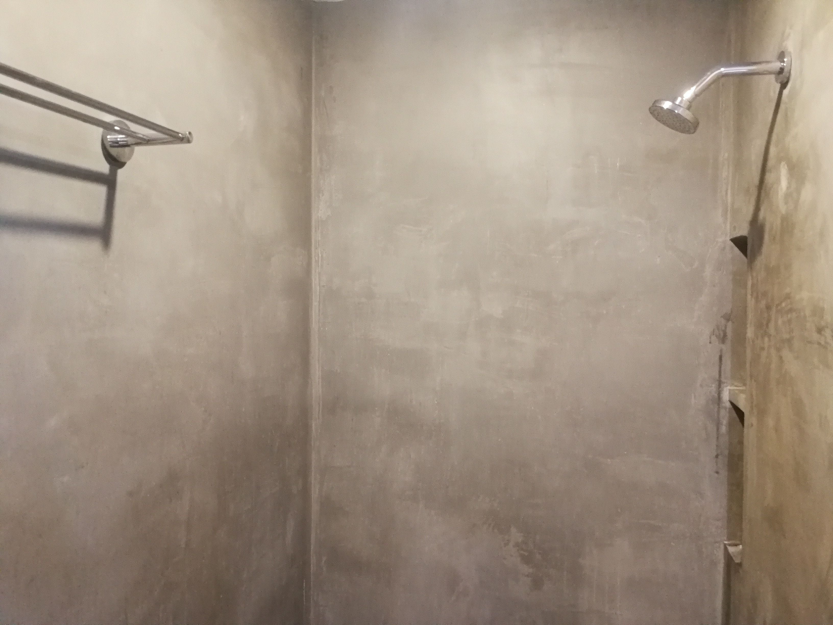 A shower with a handheld showerhead and a towel rack.