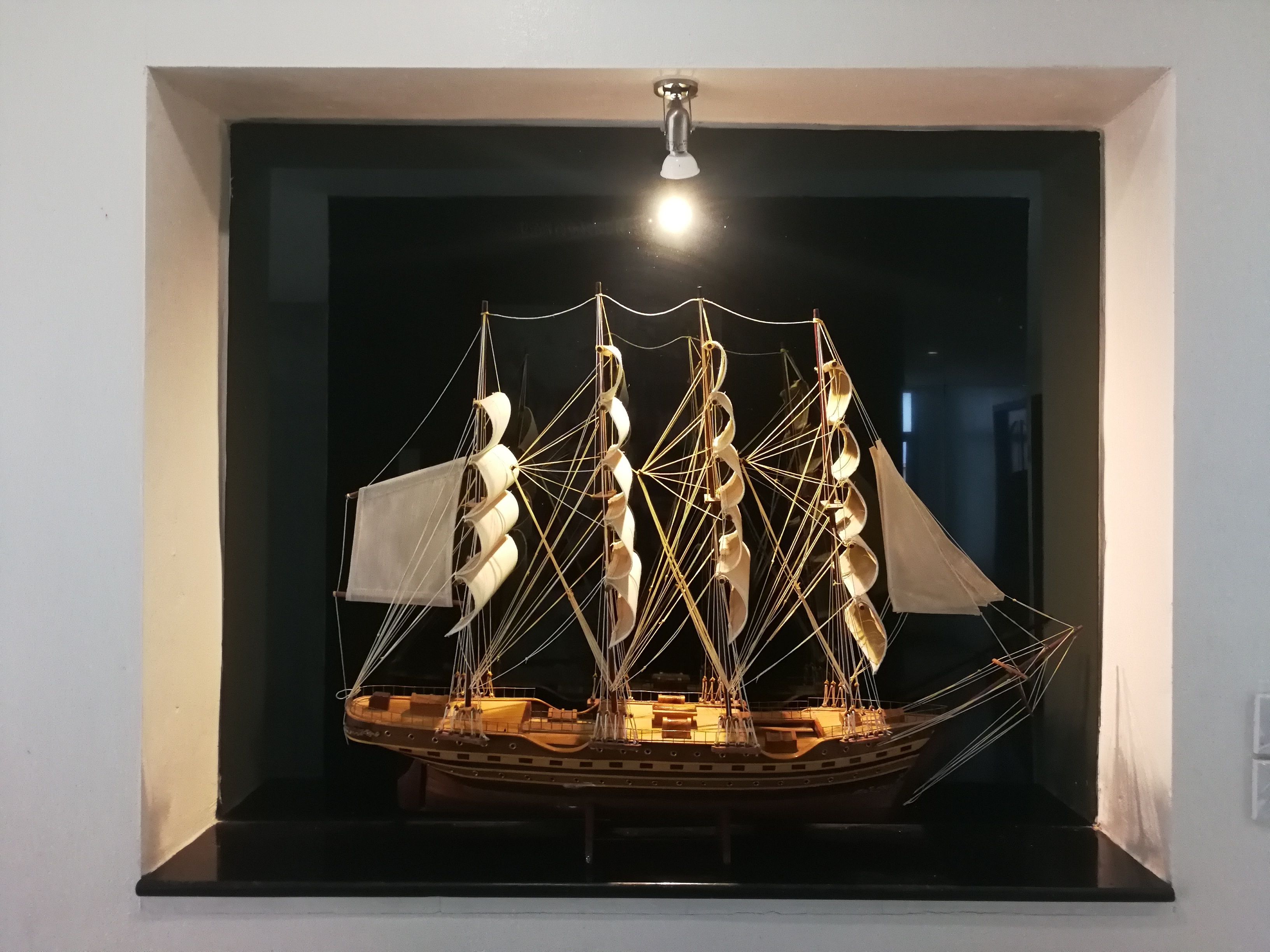 Un modelo de barco expuesto en una habitación oscura con un foco iluminándolo.