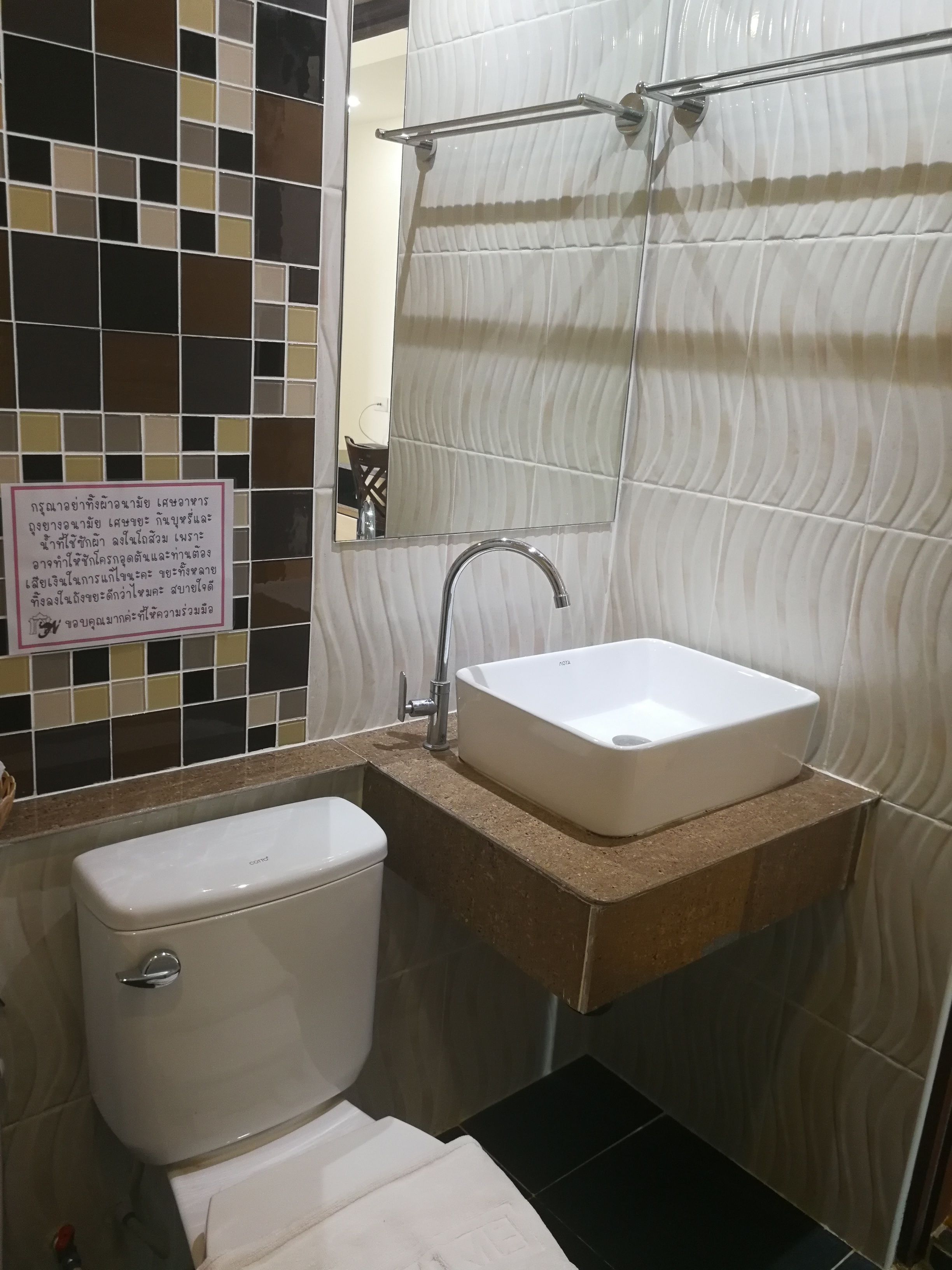 Ein Badezimmer mit einem weißen Waschbecken, einer Toilette und einem Spiegel.