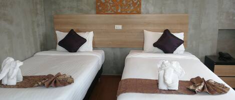 Two adjacent beds with white linens, dark and light brown throw blankets, and decorative pillows.