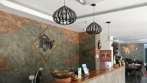 Un área de recepción con pared de ladrillo, mostrador de madera y lámparas colgantes.