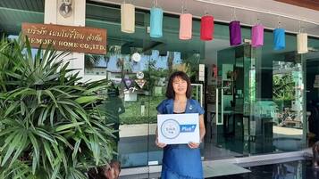A person holding a sign in front of a building with a signboard in a foreign language.