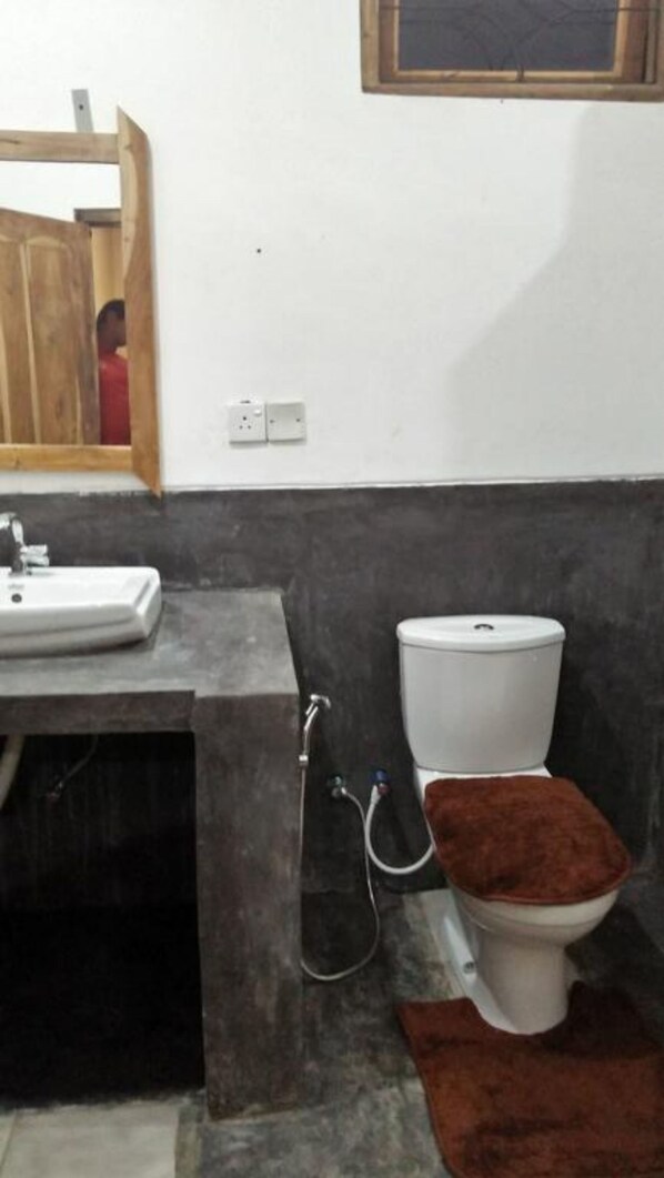 A bathroom with a white sink, a toilet, and a shower area.