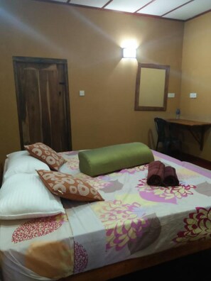A single bed with a floral bedspread, a green pillow, and multiple decorative pillows.