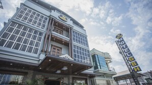 Un hotel con un cartello ben visibile, ampie finestre e un balcone.