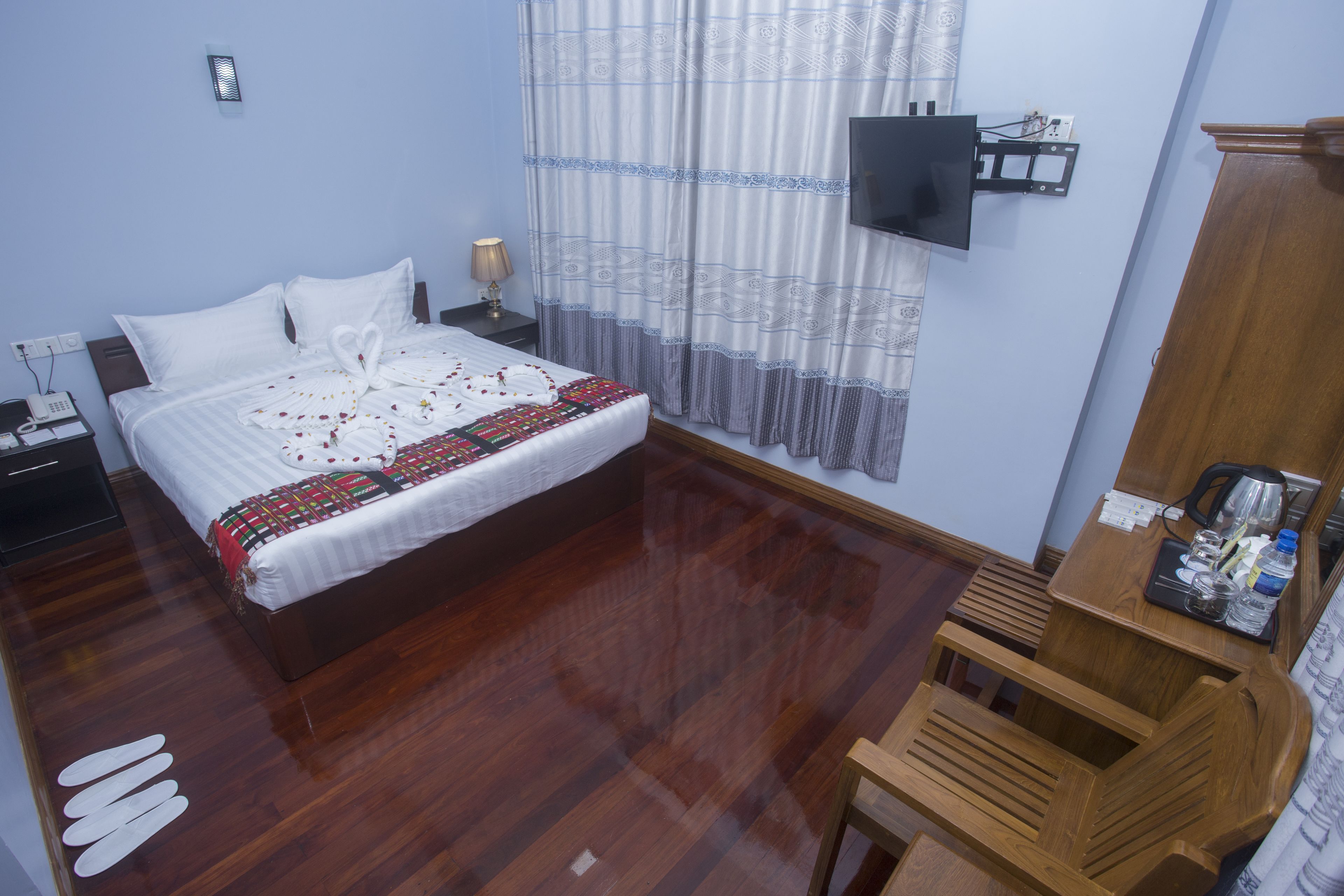 A neatly arranged bedroom with a bed, bedside table, and a mounted TV.