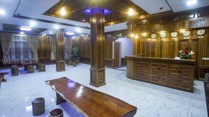 Un'area di accoglienza con una scrivania in legno, pavimento in marmo e un'ampia panca in legno.