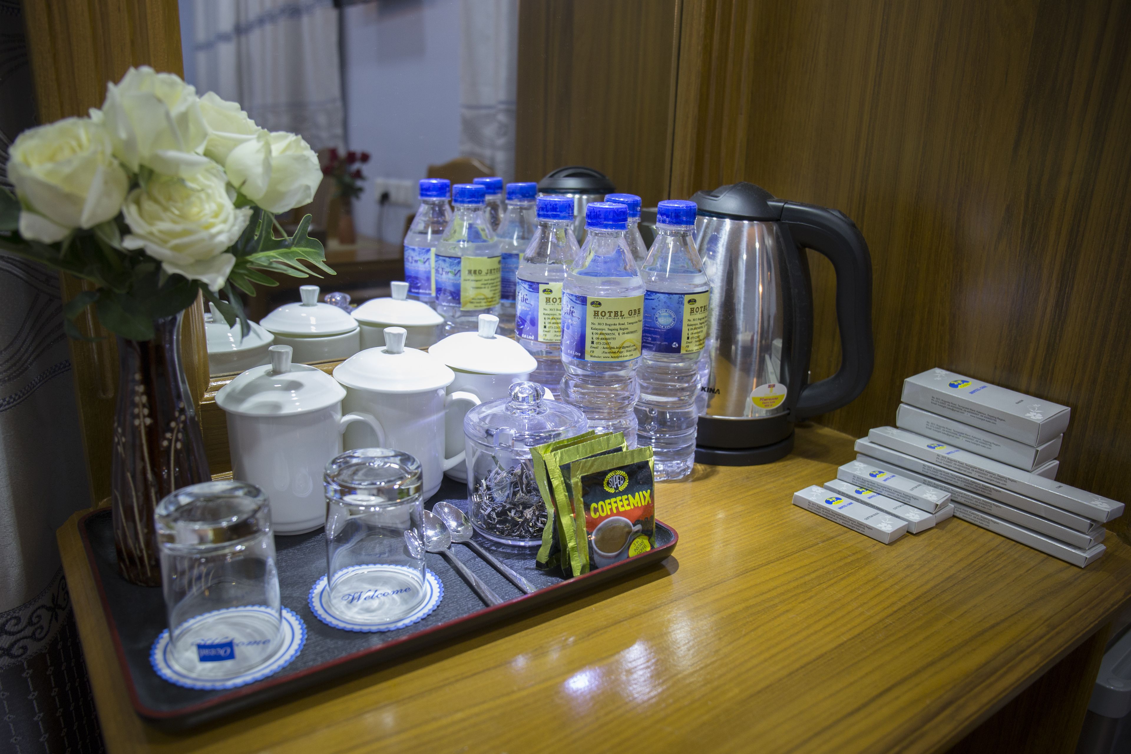 Una bandeja con elementos para preparar café, como una cafetera, botellas de agua y sobres de café.