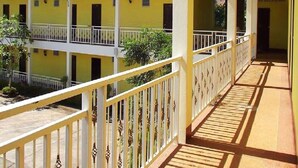 Un edificio amarillo con techo rojo, balcones blancos y una galería cubierta.