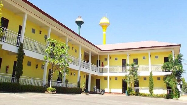 Un edificio amarillo con una torre central y un corredor cubierto.