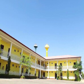 A yellow building with a central tower and a covered walkway. - Amonruk Hotel 1 (Phrae)