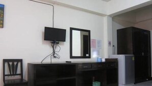Habitación con escritorio, silla, televisor, espejo, armario y refrigerador.