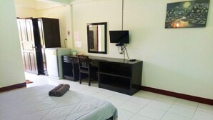 Una habitación de hotel con una cama, un escritorio, una silla, un televisor y un cuadro en la pared.