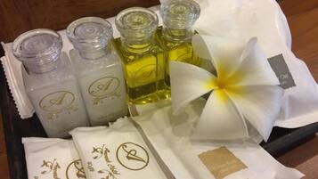 A tray with four bottles of liquid, a white flower, and two white gift bags with gold lettering.