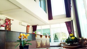 A spacious room with a large window, a wooden desk, and a potted plant. - Amonruk  Hotel 2 (Phrae)