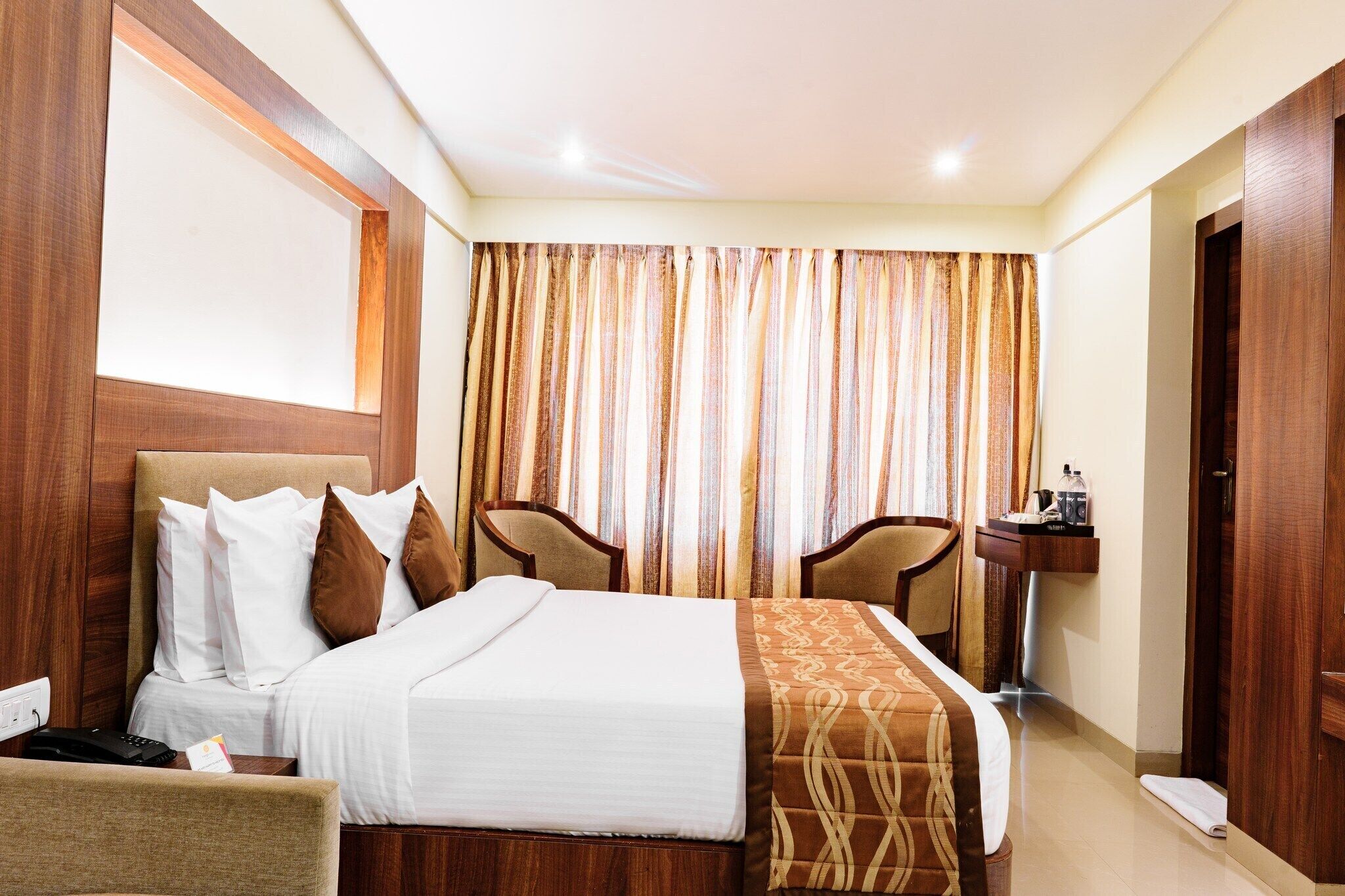 Une chambre d’hôtel avec un lit, deux chaises, une petite table et un lavabo.
