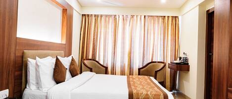Une chambre d’hôtel avec un lit, deux chaises, une petite table et un lavabo.