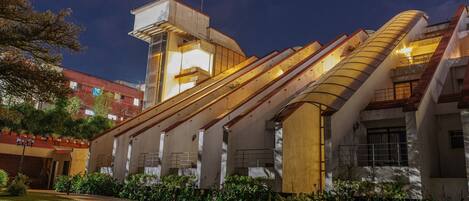 Un edificio moderno con un diseño arquitectónico único, que presenta balcones curvos y una escalera central.