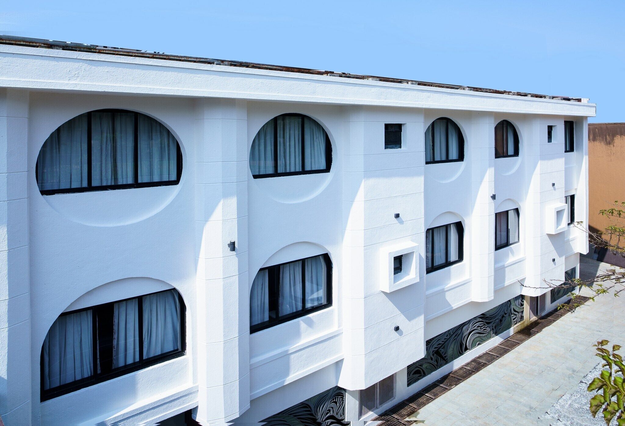 A white building with multiple arched windows and a flat roof.