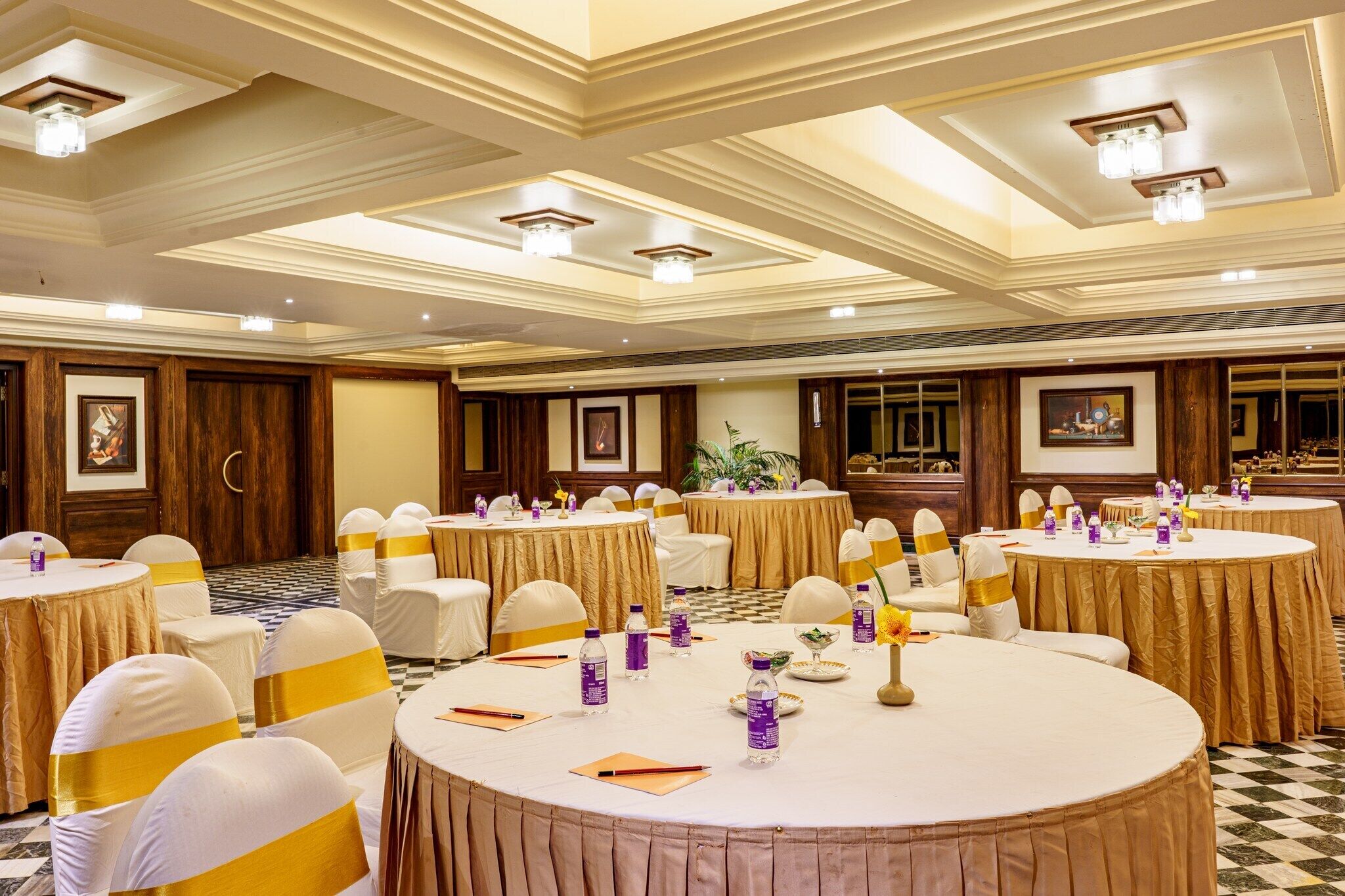 A banquet hall with round tables, chairs, and centerpieces.
