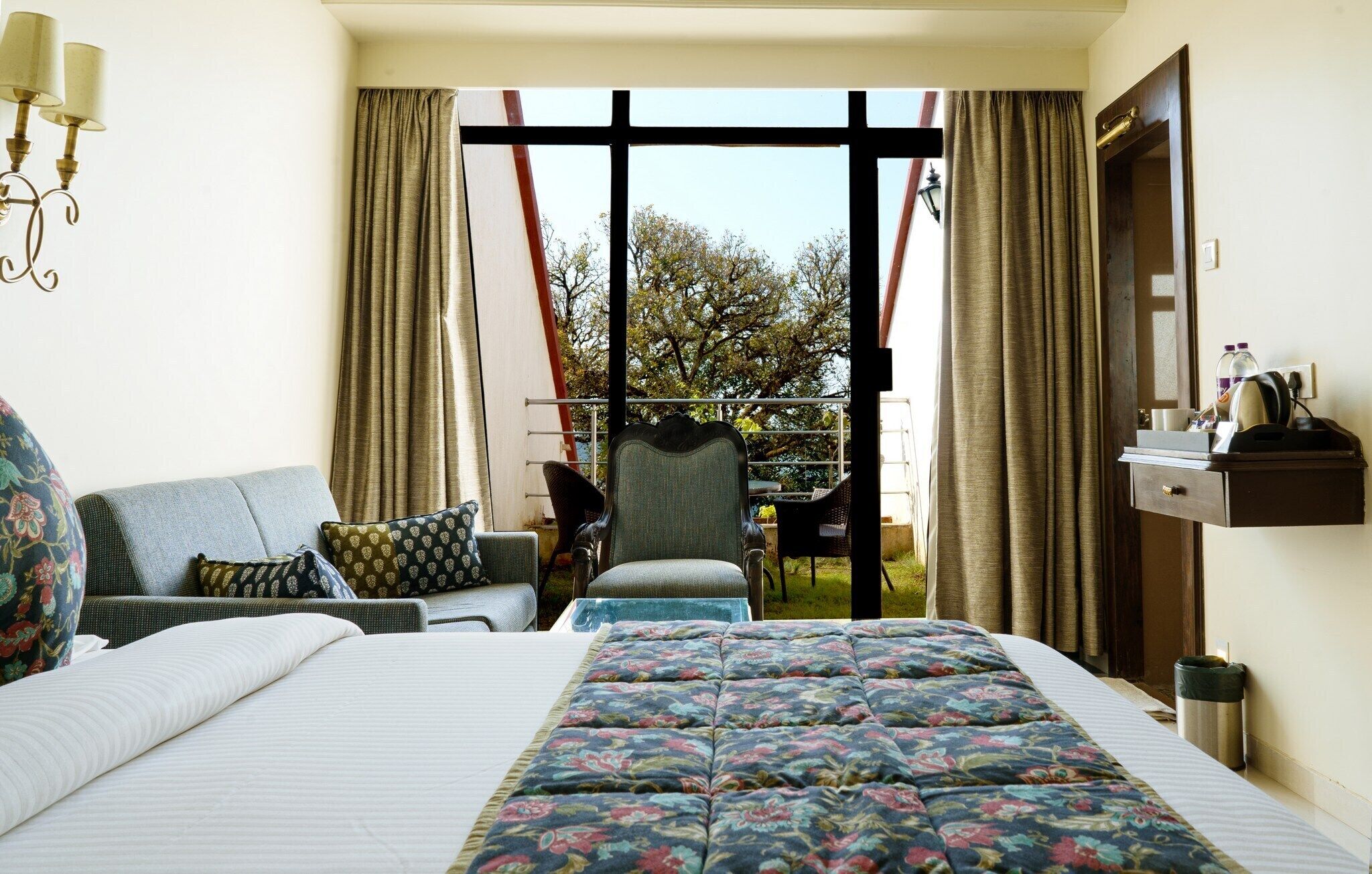 Une chambre d’hôtel avec un lit, un canapé, une chaise et un balcon avec des rideaux.