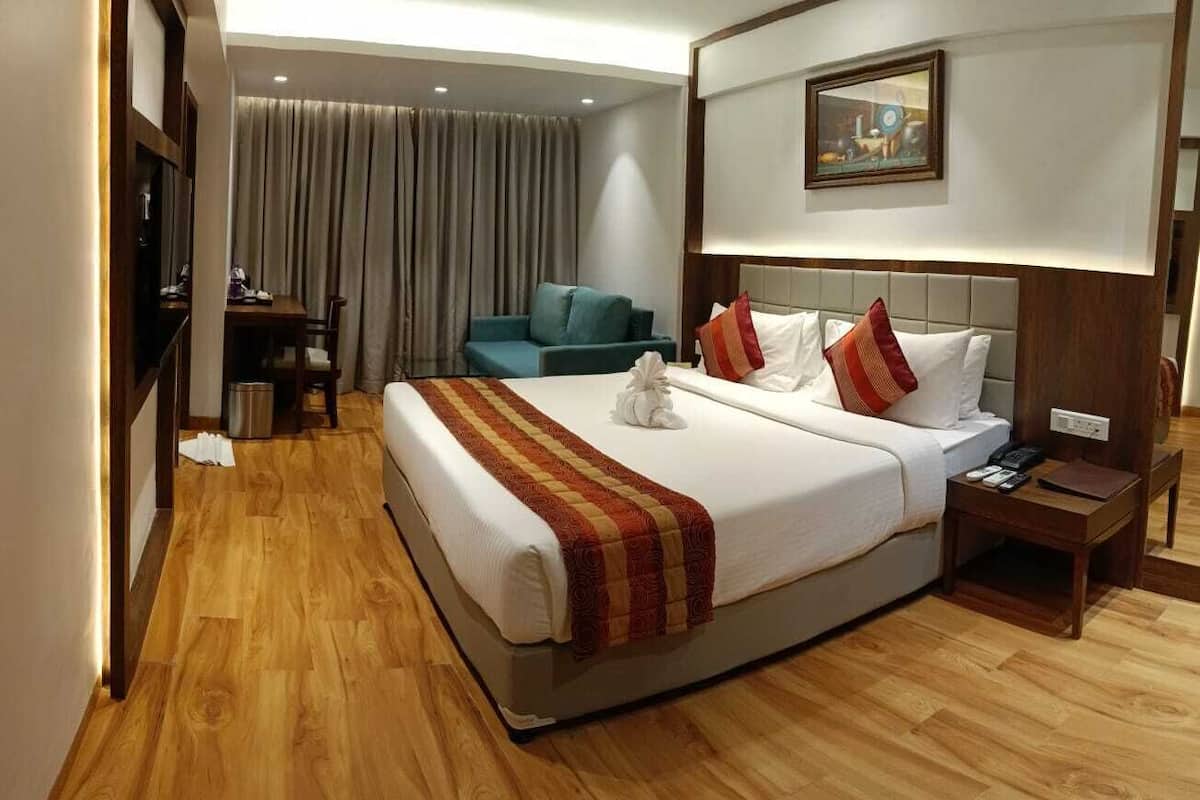 A hotel room with a large bed, a desk, a chair, a TV, and a painting on the wall.