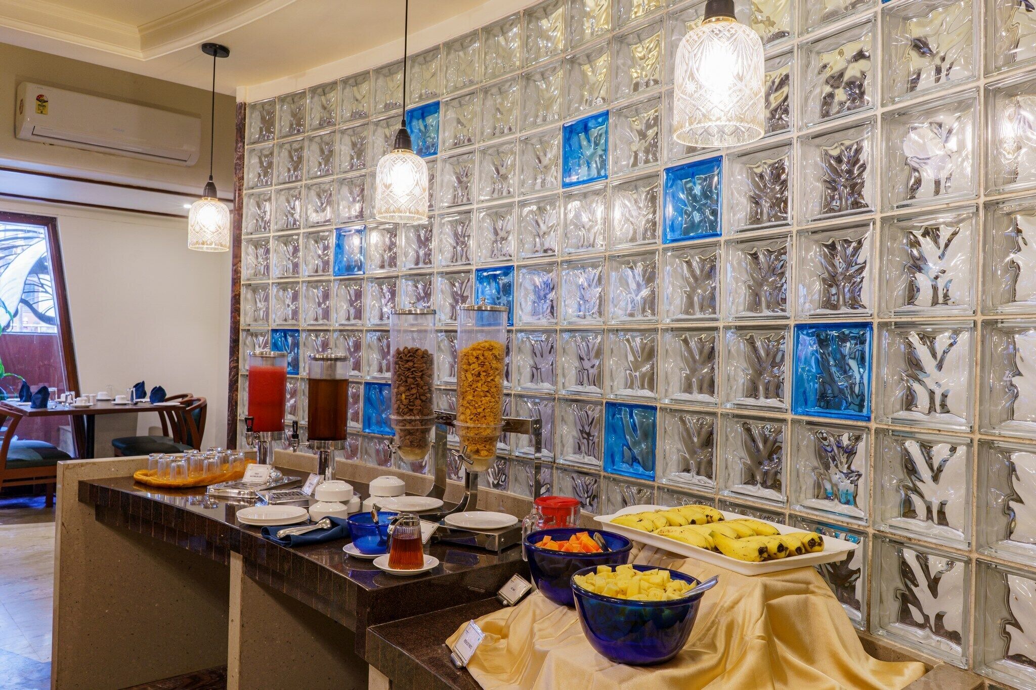 A buffet area with various food items and a wall of decorative glass panels.